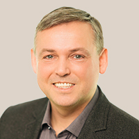 Dr. Philipp Eigenwillig trägt ein dunkles Sakko und ein helles Hemd vor hellem Hintergrund