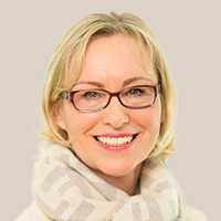 Dr. Katja Feyer, BDK Landesvorsitzende Bremen, mit blondem Haar, trägt einen hellen Schal und ein beiges Oberteil vor hellem Hintergrund