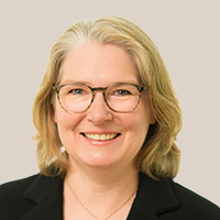 Dr. Agnes Römeth, BDK Landesvorsitzende Nordrhein, mit schulterlangem blondem Haar, schwarzem Blazer und goldener Halskette vor hellem Hintergrund